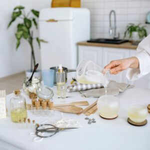 Person pouring gel wax to make candles in a home kitchen setup with tools and materials.